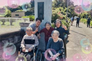 施設の屋外で車椅子利用者を含む複数の入居者と職員が集合している写真